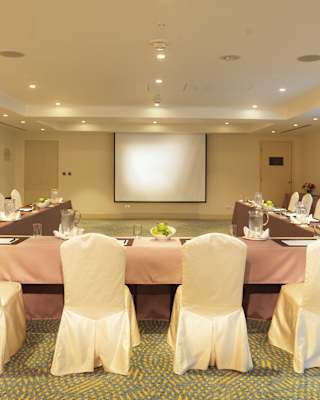 Banquet tables in a U-formation with satin pink tablecloths set for a meeting