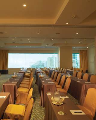 Rows of banquet tables facing a screen topped with pens and pads