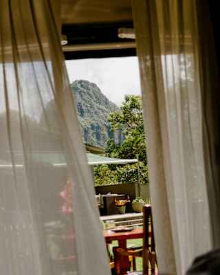 Drapes shift in breeze through a suite door, revealing a view of the imposing Huayna Picchu beyond Sanctuary Lodge's gardens.
