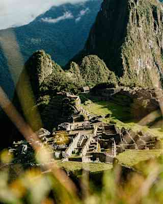 View down over the citadel of Macha Picchu, cradled between Huchuy Picchu and Huayna Picchu, seen from a grassy viewpoint.