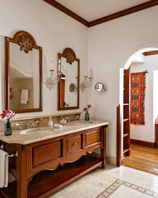 View of a large twin basin unit with a marble top and wooden base, and two wall-mounted mirrors, in a bathroom detail.