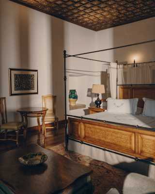 Sunlight plays with shadows in a Nazarenas Suite bedroom, with a wood-panelled four-poster bed and hand-crafted ceiling.