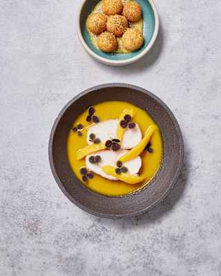 Two pieces of white Paiche in high jungle juices with Cocona, Rugoso lemon and yuca, and a bowl of croquette-like balls.