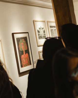 People looking at framed artwork in a gallery.