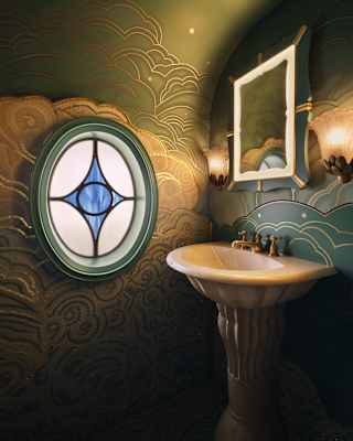 A small bathroom with ornate green and gold patterned walls, a pedestal basin, a square mirror with two wall lights, and a round stained glass window featuring a blue diamond shape.