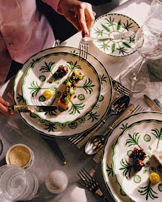 A guest raises a knife and fork, ready to enjoy a terrine with chutney, served on Sultan's Garden crockery, seen from above.