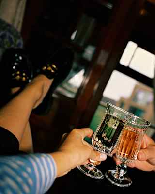 Angled image of two guests chinking flute glasses of Champagne, seen in close-up.