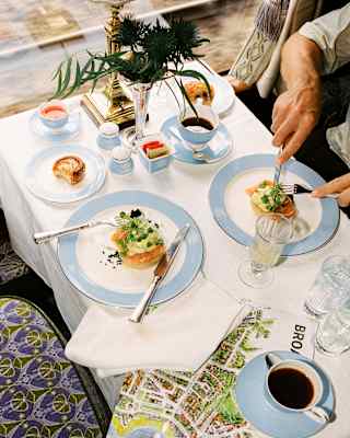 Looking down on a dining table as a guest tucks into one of two plates of salmon, while his companion's seat is empty.