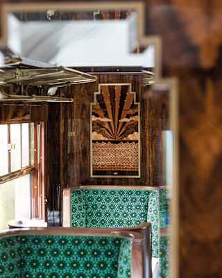 Narrow triangles of alternate dark and pale wood marquetry fan out in an art deco sunset, framed by symmetrical clouds