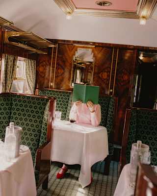 Angled image of a guest at a Cygnus carriage table as she holds a green menu, complementing the décor, in front of her face.