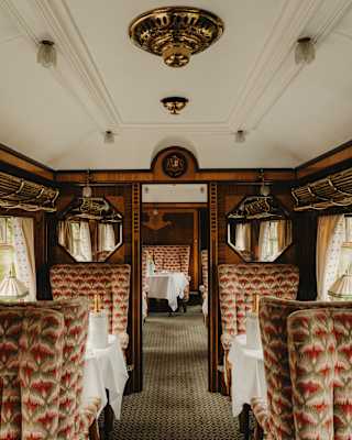 A view through the Zena Car highlights its old-time style and comfort with large grey and pink-patterned upholstered seats.
