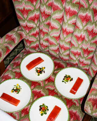 Four plates of salmon fillets with cream and edible flowers sit on a Zena car chair, complementing its pink and green fabric.