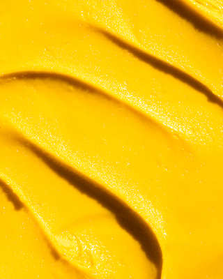 Close-up of unctuous mango-hued gelato, rippled and glossy in the sunshine.