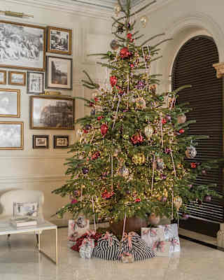 A tall Christmas tree, with baubles and tinsel in red and gold, creates a true festive splash in the white marble lobby.