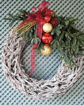 A simple and tasteful Christmas wreath made with latticed wood, fir sprigs and gold and red baubles, tied with red ribbon.