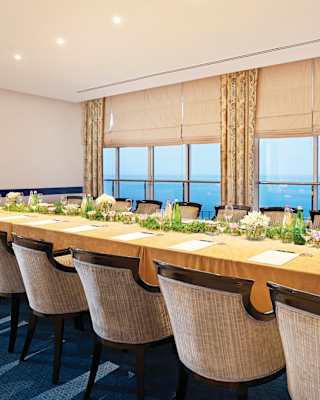 Boardroom table set for a meeting in a light and airy meeting room with sea views