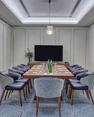 Wood-panelled room with blue leather chairs and a table set for a meeting
