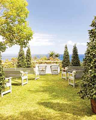 A corner of the exotic gardens overlooking the sea is ready for a memorable occasion with a wedding table and bench seating.