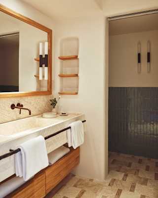 A basin unit with a towel rail, under-drawers, and wall mirror runs along one side of the Villeggiatura Garden Room bathroom.