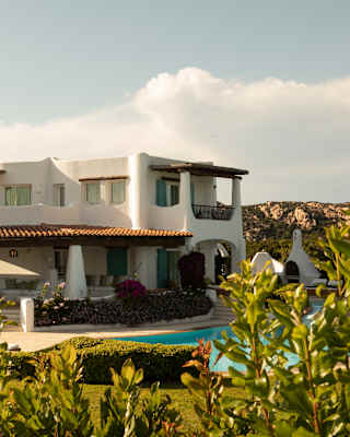 A five-bed villa sprawls in private gardens with balconies and terraces tucked within its white edifice, overlooking a pool.