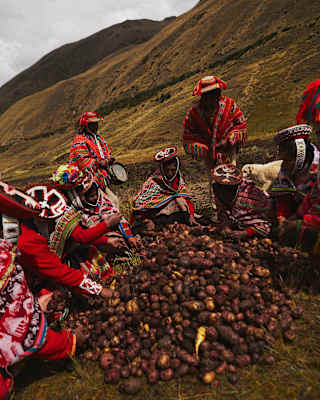 Dressed in traditional weaves, local men and women sit around a mound of potatoes, harvested as an offering to Pachamama.