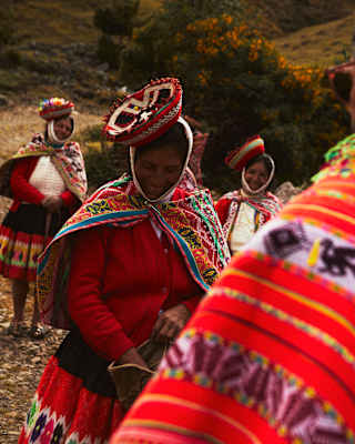 Angled image of three local women wearing tilted Montera hats and brightly woven Manta shawls over Jobona jackets for warmth.