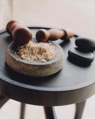 Close-up detail of a small black table with a shallow stone mortar of rock salt and two wooden pestles.