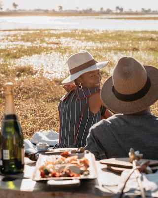 Smiling couple sitting on a blanket with a luxurious picnic spread and champagne