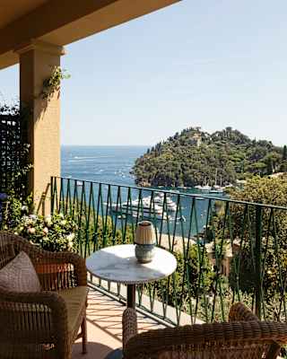 View from a Premium Room terrace over the stunning Baia Cannone, where two cruise ships pause in the blue between hills.