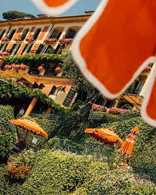 Angled view of the peach-hued hotel, dripping with green climbers and pink balcony blooms, seen from under an orange parasol.