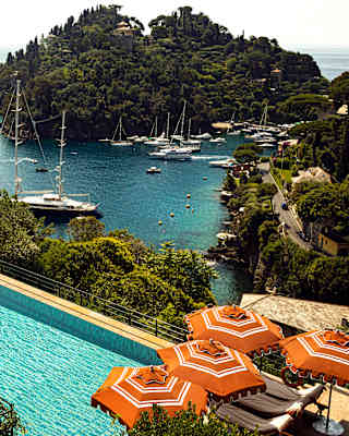 Terracotta parasols pepper the sun terrace beside the aquamarine pool. Far below the wooded cliff, yachts moor in the harbour