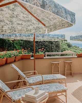 On Spa Dior's terrace, four side tables, loungers and parasols, with furnishings in Toile de Jouy, soak up sun and views.