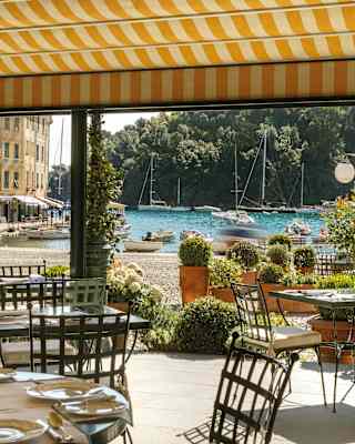 View from beneath the yellow striped terrace canopy of Dav Mare over pretty La Piazzetta to the quaint sparkling blue marina.