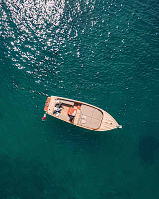 From above, deep bluegreen water surrounds a gozzo boat