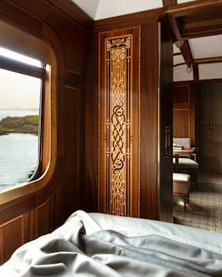 A panel with intricate Celtic knot marquetry flanks the bedroom door close to a window with sea views, seen from the bed.