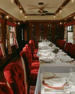 A line of white tables is bordered by deep red velvet chairs, which creates an air of decadence in the Raven dining car.