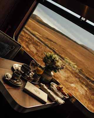 Sharply angled view of breakfast, delivered to a cabin and resting on a window table with views over bronze grass plains.