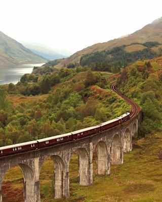 Aerial view of The Royal Scotsman as it crosses the Glenfinnan Viaduct on a damp and misty day, with views of Loch Shiel.