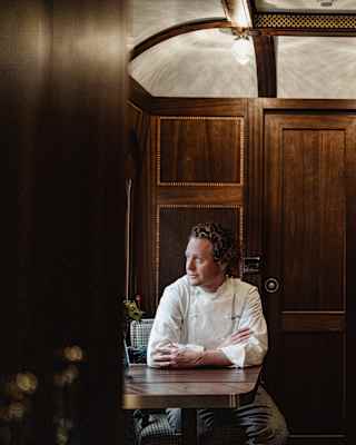 Chef Tom Kitchin sits in the Grand Suite looking out of the window, which illuminates his face in the warm wood surrounds.