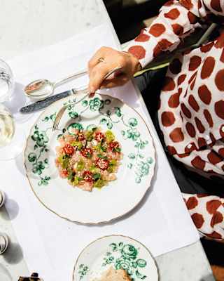 Looking down on a pretty plate of Amberjack Tartare with tomatoes and toasted sesame seeds, served with white wine and bread.