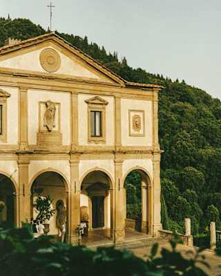 The front of Villa San Michele, with its Renaissance archways and stone hues of cream and ochre, illuminated by sunshine.