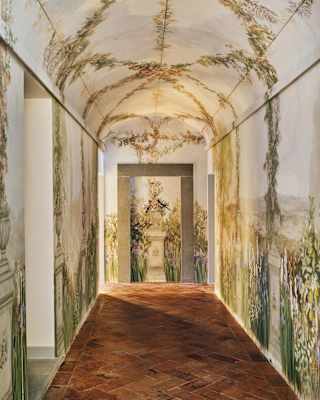 Beautiful vine murals climb the walls and cross the arched ceiling of a vault-like spa corridor with terracotta tiling.