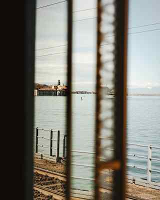 A view from the train, divided and refracted by a half-open window, reveals distant buildings on the Venetian lagoon.