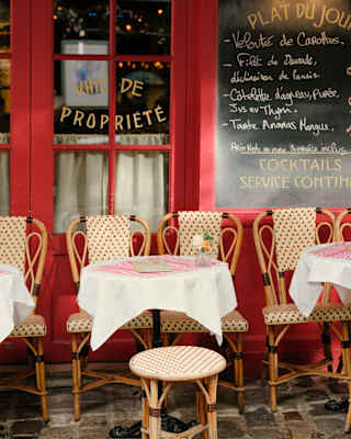 Round tables and cane bistro chairs line the rouge-framed windows and chalk board outside La Mère Catherine in Monmartre.