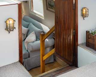 View from the top of Alouette down steps, flanked by lights, through an open door to a lounge with a plump pale blue sofa.