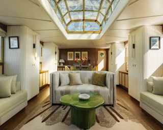 A glass ceiling lantern spills light into the lounge, furnished with sage and soft grey banquettes and sofa, with wood fittings.