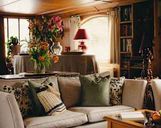 The lounge area with bright windows, floor-to-ceiling book cases and sofas and soft furnishings in a variety of fabrics.