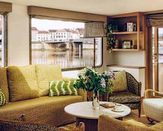 View of Lilas's living area with a lime-yellow sofa, four armchairs with grey and green furnishings, and wooden coffee table.