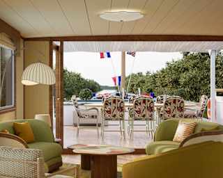 View through Marguerite's living area and open bifold doors to the deck and an outdoor table and chairs with floral cushions.