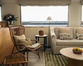 Cream and moss cushions on a cane chair marry with a beige sofa and green rug to create a natural décor theme in the lounge.